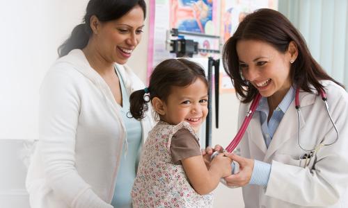 Pediatric nurse practitioner smiling taking heart rate of toddler patient