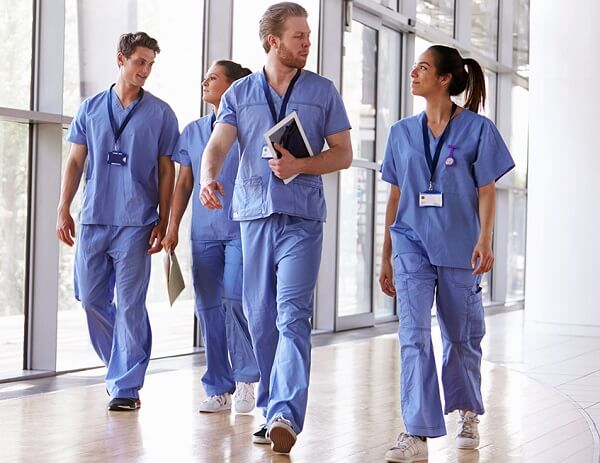 Different Types of Nurses Walking Through Hospital Corridor