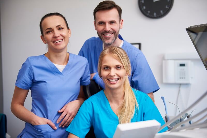 Team of medical assistants smiling at desk