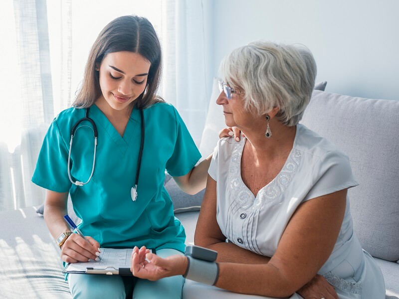 Medical assistant smiling with elderly patient taking patient history