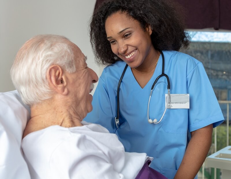 Medical assistant wearing stethoscope smiling with elderly patient