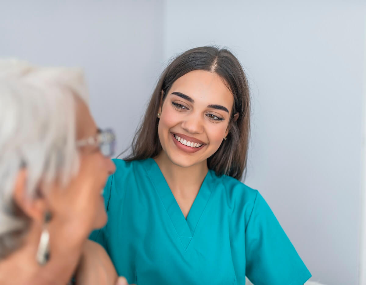 Medical Assistant Smiling at Elderly Patient in Health Clinic