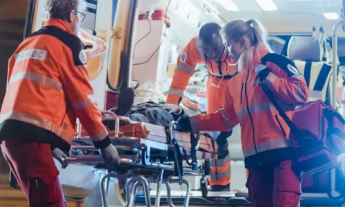 EMS Team of Associate Degree Paramedics Loading Injured Patient Into Ambulance