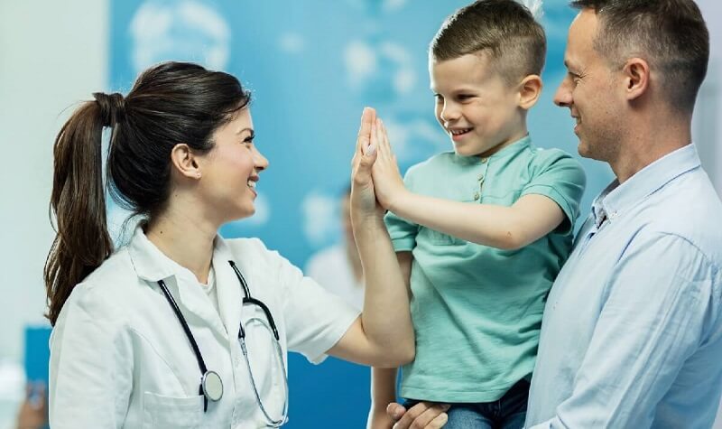 Family Nurse Practitioner High Fiving Young Patient with Dad