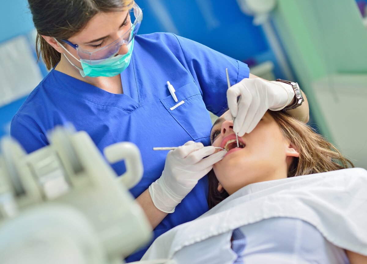 Dental Hygienist in Dental Office Cleaning Teeth