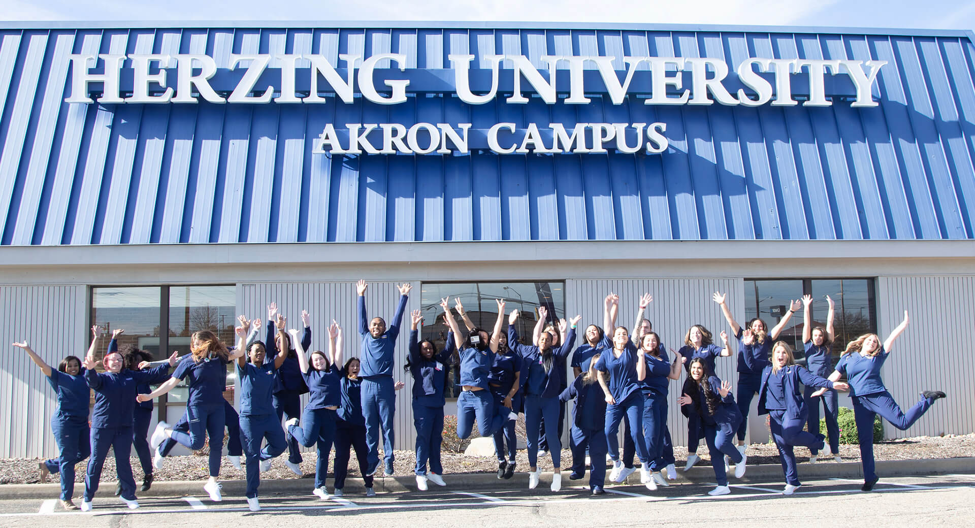 Akron Campus Nursing Graduates Celebrating in Front of Campus Entrance