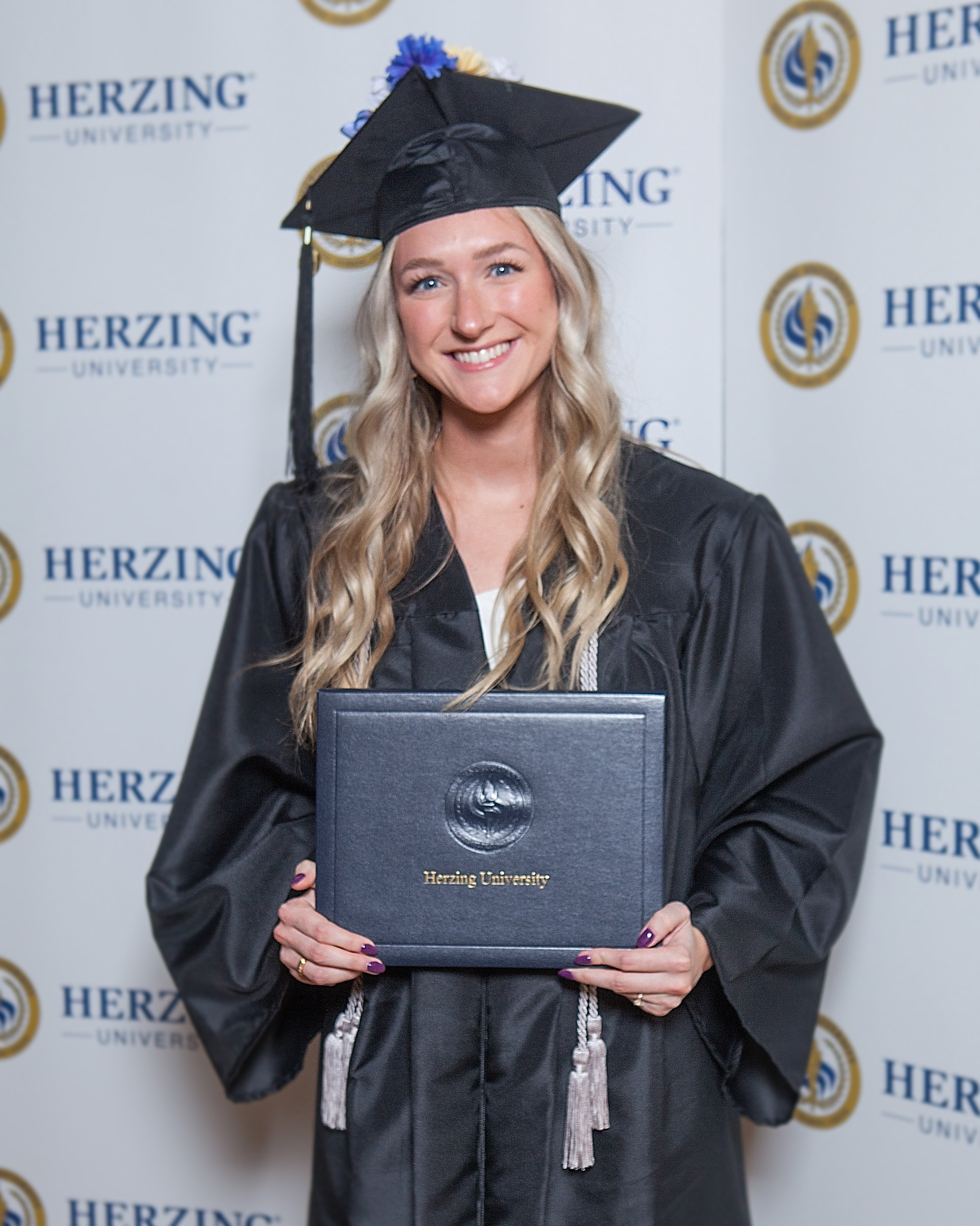 Herzing graduate smiling and holding degree