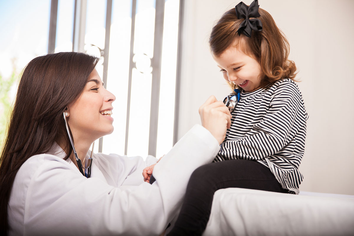 Pediatric Nurse Practitioner Smiling with Young Patient Reading Heart Rate with Stethoscope