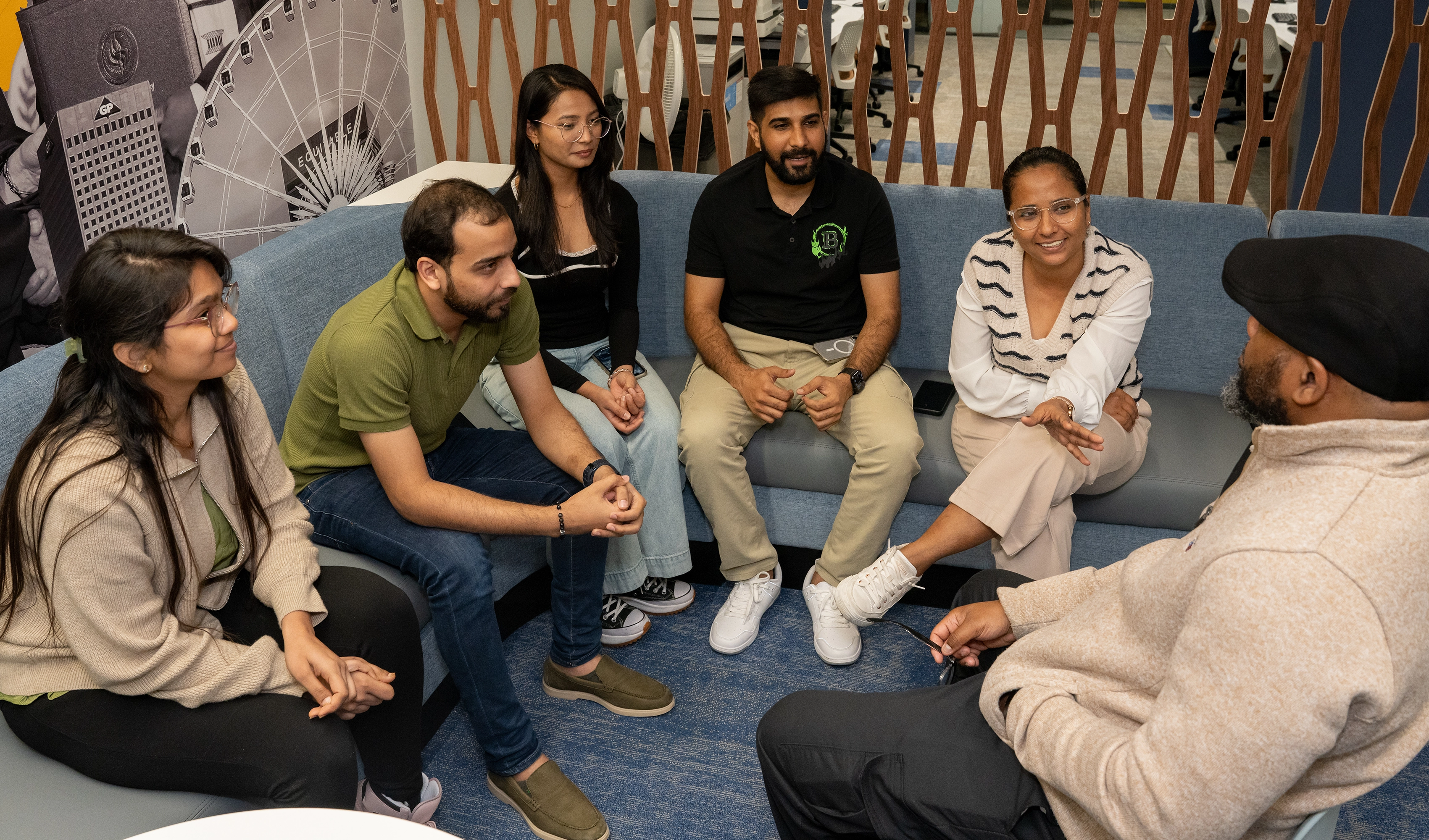 Herzing University international students engaged in a group discussion with a staff member in a campus lounge.