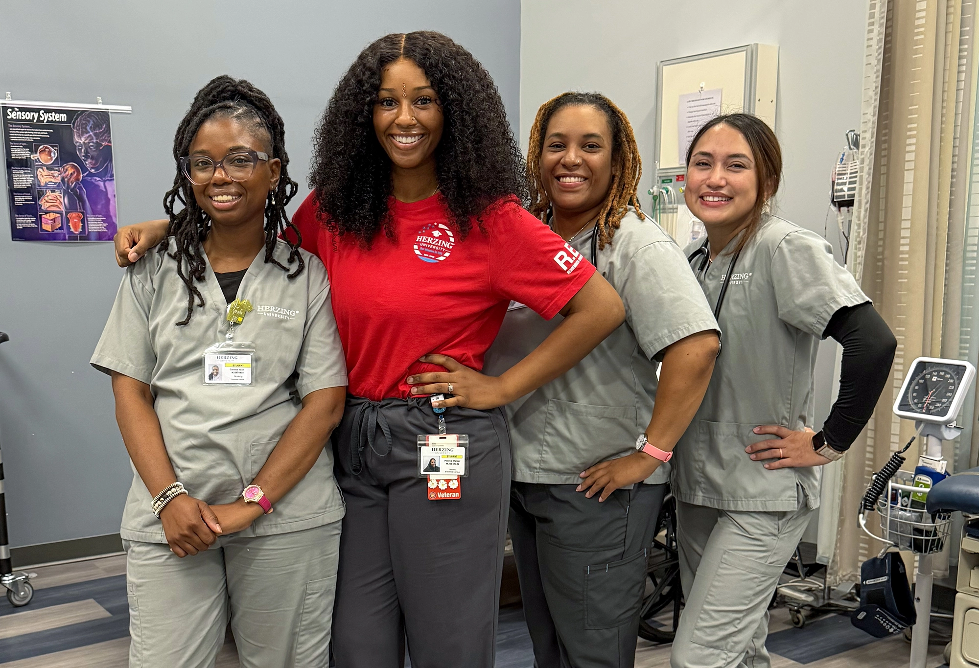 Group of Brookfield campus nursing students in scrubs and lab coats smiling together in clinical training lab.
