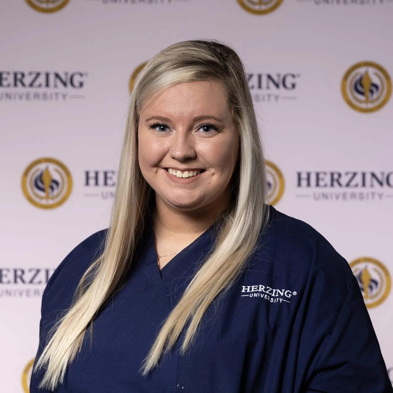 Close-up of a Herzing University medical assisting student in branded navy scrubs, highlighting dedication and achievement.