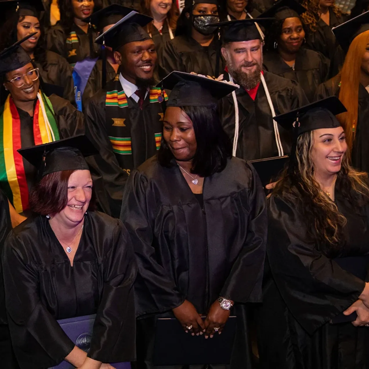 Herzing University graduates smiling and celebrating together during commencement ceremony.