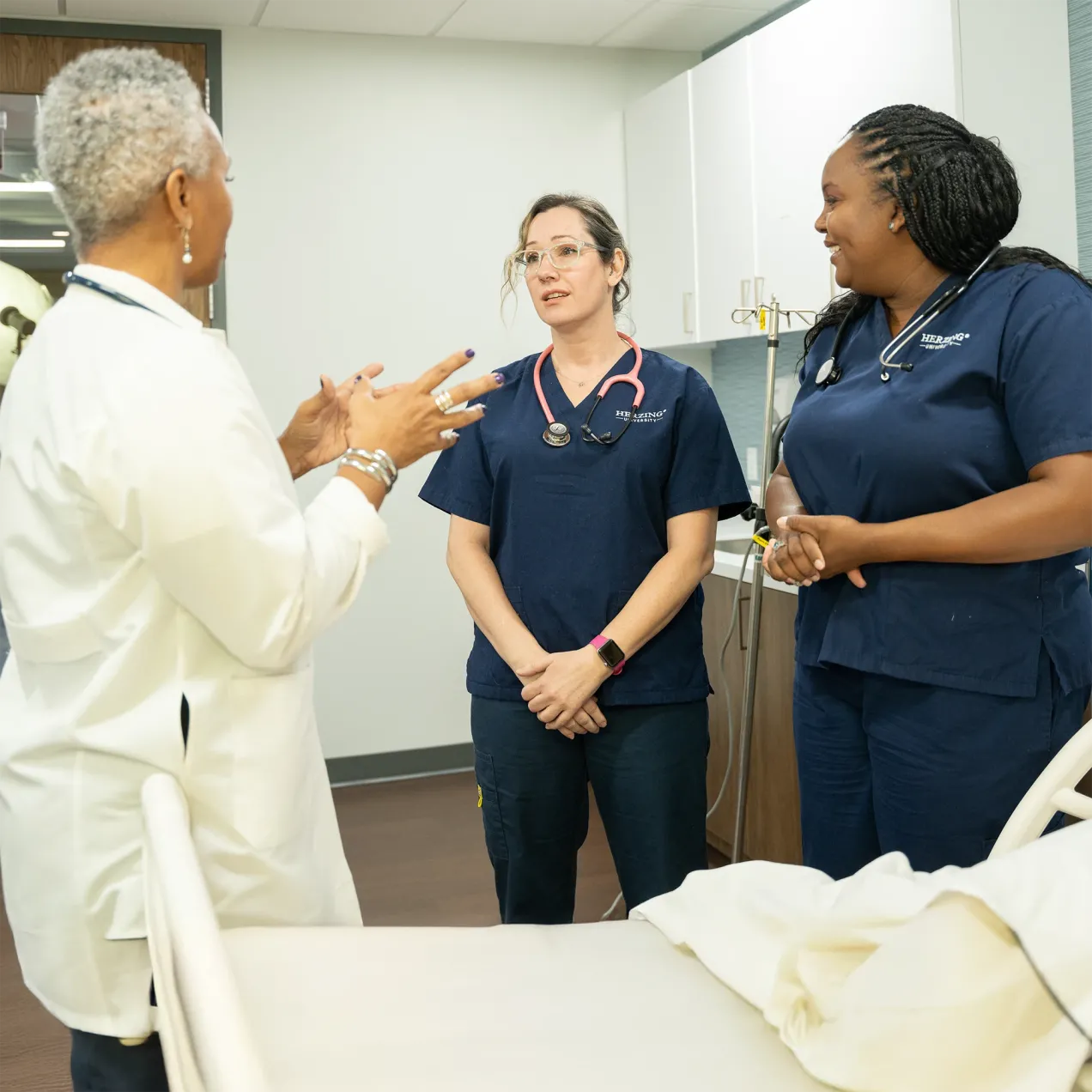 Herzing University nursing preceptor mentoring two nursing students during clinical training in a simulated healthcare setting