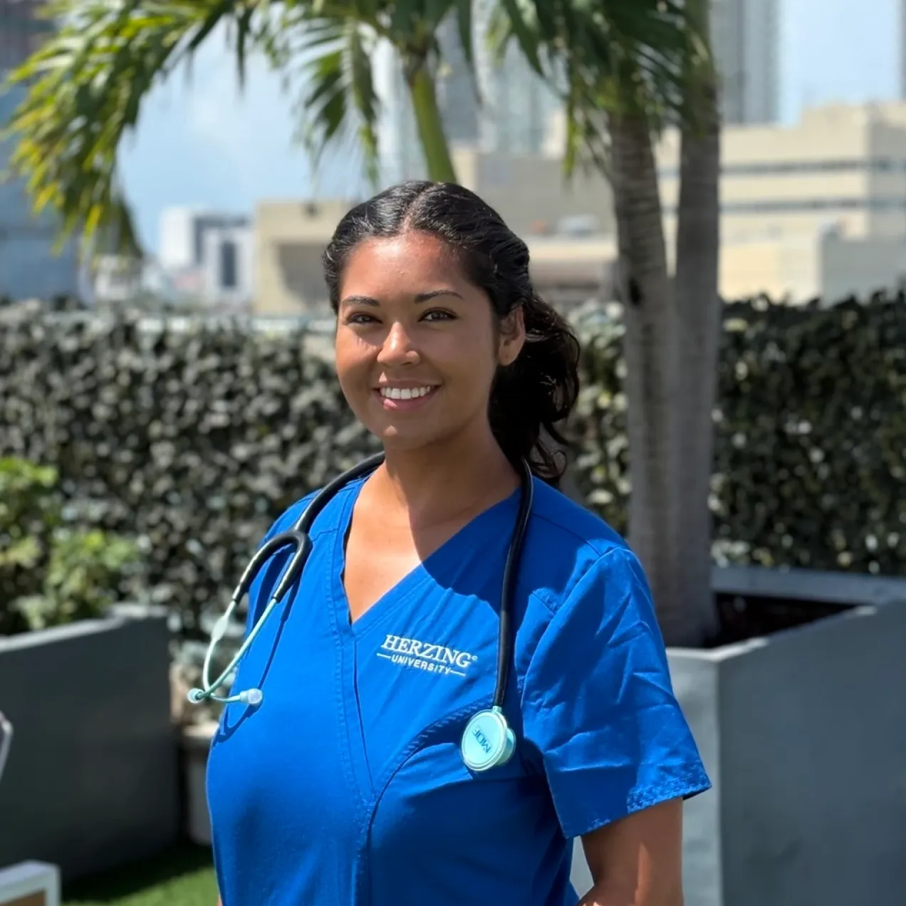 Herzing nursing graduate wearing blue scrubs outside