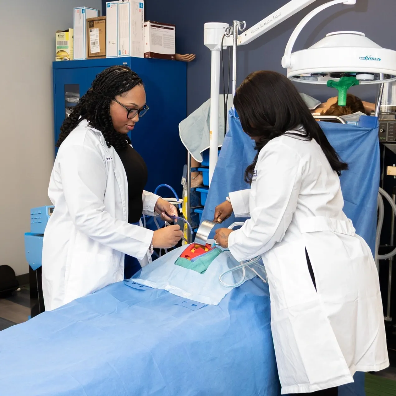 Two Herzing University Surgical Technology students practicing procedure in campus lab environment