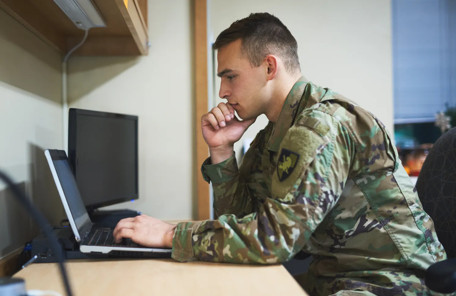 Shot of a young soldier using a laptop at a desk