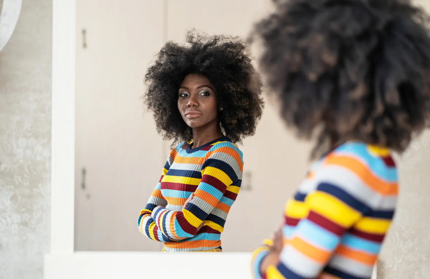 Woman with afro looking at her reflection in the mirror