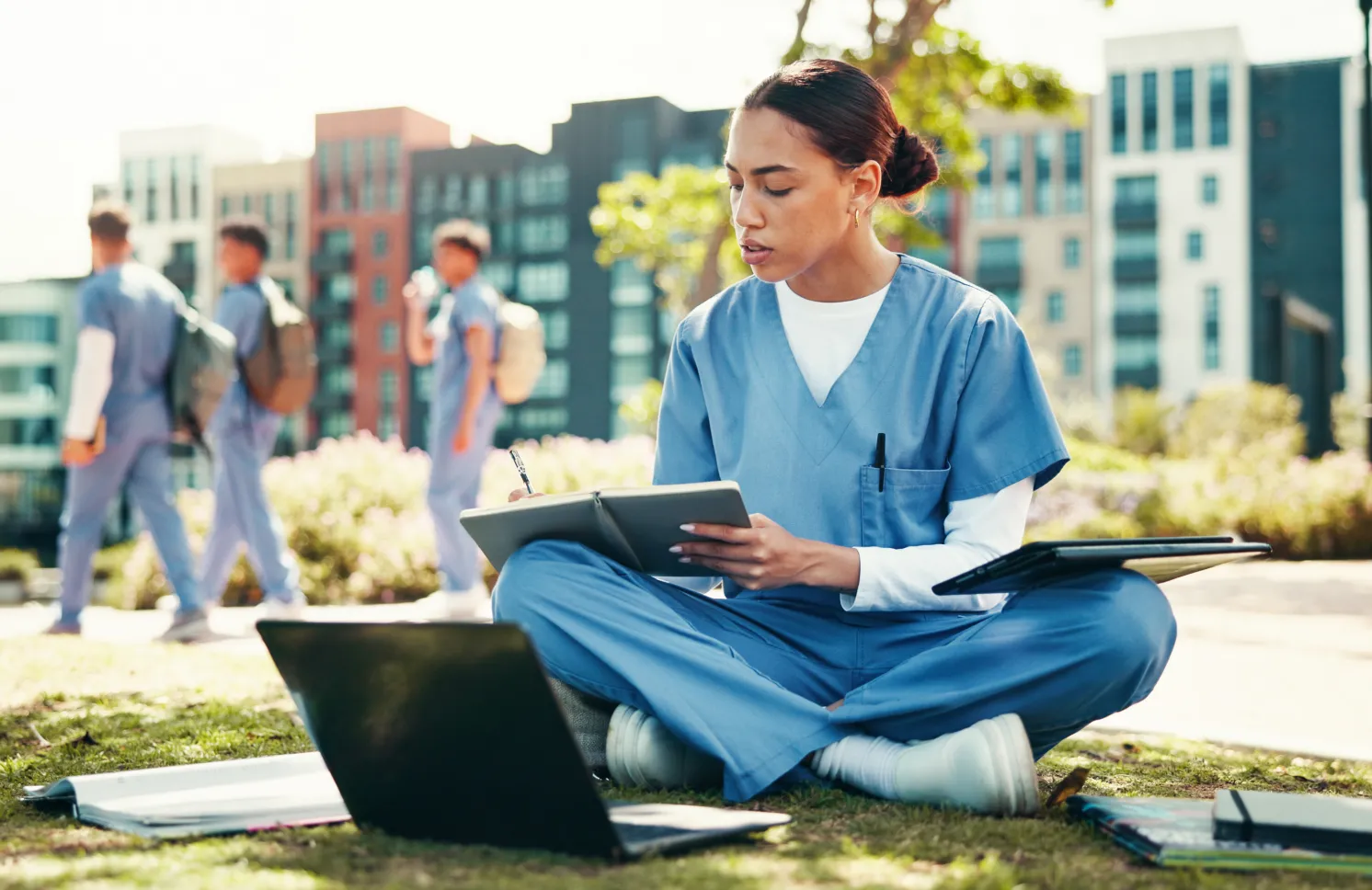 Woman, nurse or student writing with book for internship, studying or research at med school. Female person, healthcare candidate or intern taking notes with laptop for medical exam or test at campus