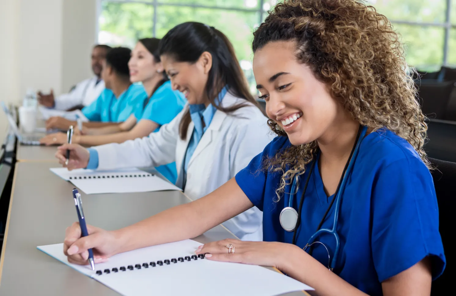 Beautiful female medical or nursing school student smiles as she takes notes during class.