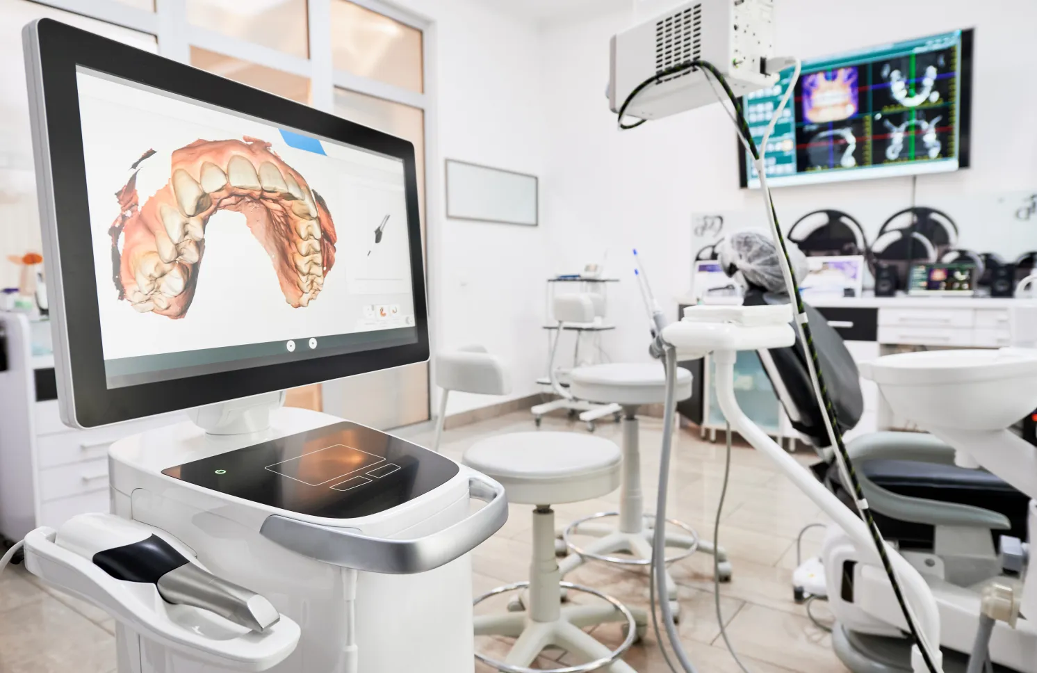 Interior of dental office with modern equipment and dental intraoral scanner with teeth on display, medical system for intraoral scanning. Concept of digital dentistry and dental scanning technology.