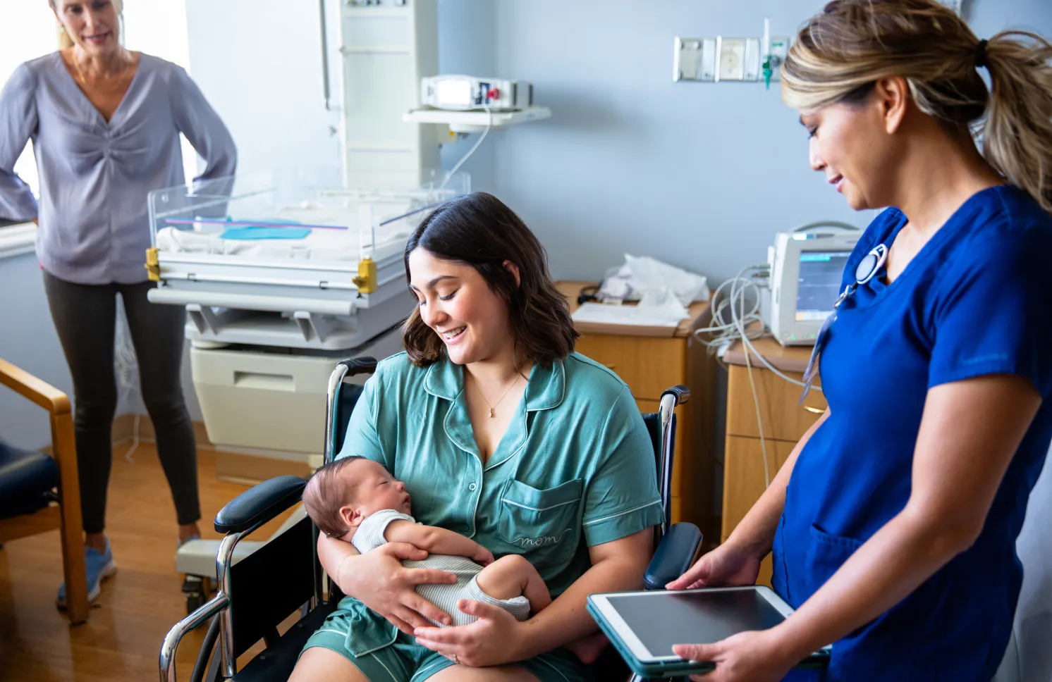 A young family consisting of a hispanic father and mother and their newborn baby boy in the hospital with grandparents, a nurse, and a pediatrician.