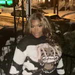Woman in a colorful sweater posing on front porch in the winter surrounded by snow