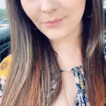Woman poses in a car in a bright yellow sweater