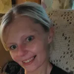 Woman posing for a selfie on a couch with a white crochet blanket behind her