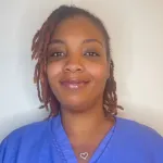 La Tonya Henry posing for the camera in scrubs behind a white backdrop