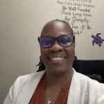 Professional African American nurse in a lab coat sitting in her office
