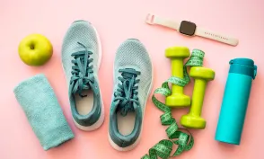 Healthy lifestyle and fitness concept. Sneakers, dumbbells, towel, green apple and fitness bracelet.