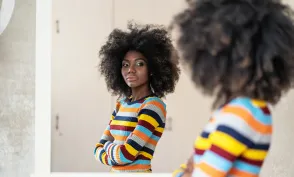 Woman with afro looking at her reflection in the mirror
