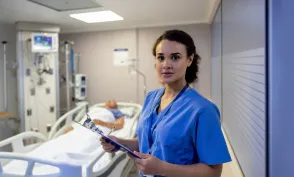 Portrait of a Latin American nurse working at the ICU and checking on a patient - healthcare and medicine concepts
