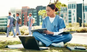 Woman, nurse or student writing with book for internship, studying or research at med school. Female person, healthcare candidate or intern taking notes with laptop for medical exam or test at campus