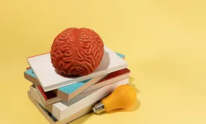 A brain, a bulb and books on yellow background, creative concept, ideas.