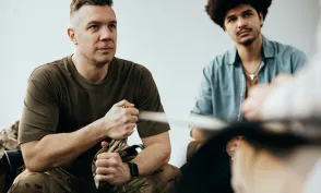 Military officer listening to therapist while having group therapy meeting at community center.