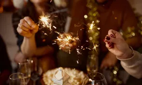 Close up of unrecognizable friends having fun with sparklers while celebrating Christmas at home.