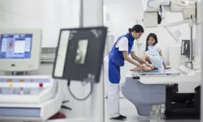 Radiologic technologist assisting a small child at an x-ray machine