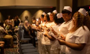 Herzing University Nurses standing with pinning lamps at the Herzing pinning ceremony