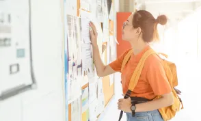 Unemployed young university woman looking for work or job after graduation at the post board
