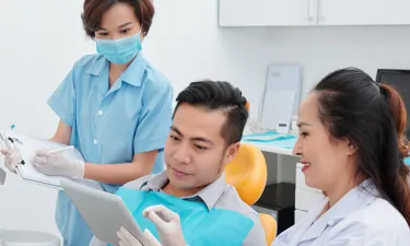 Dental Assistant with Diploma Helping Dentist Consult with Patient