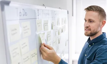 Marketing Student Organizing Tasks with Sticky Notes on Whiteboard