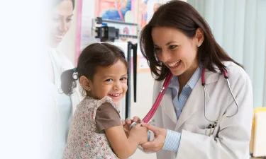 Nurse Practitioner Smiling with Child Patient Taking Heart Rate