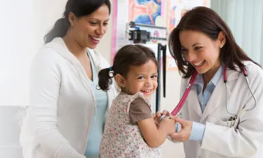 Nurse Practitioner Smiling with Child Patient Taking Heart Rate