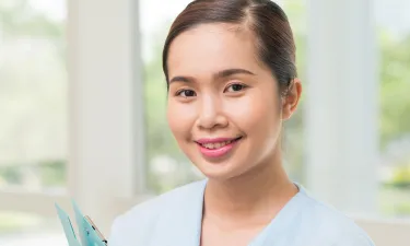 Medical Assistant Holding Clipboard Smiling in Hallway