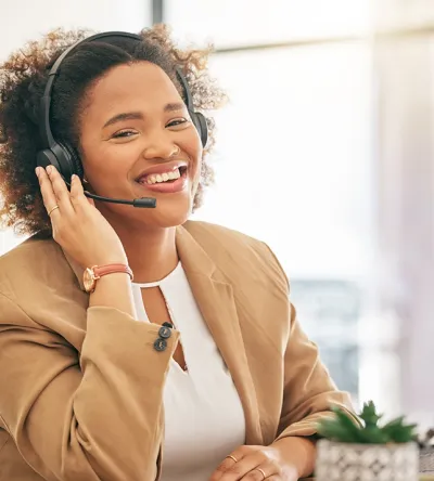 Professional woman in a headset smiling while working at a desk, representing a career in insurance billing and coding.