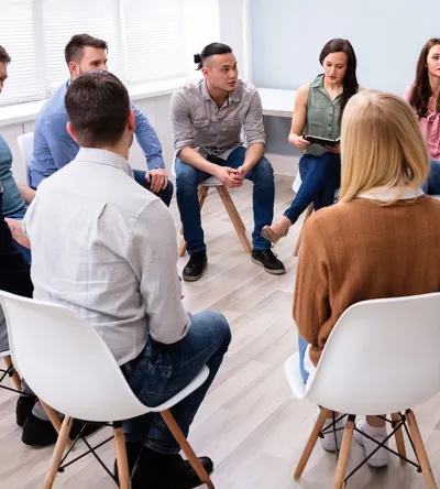 Group of diverse individuals participating in a supportive counseling session, representing social work practice skills taught in Herzing University’s Master in Social Work program.