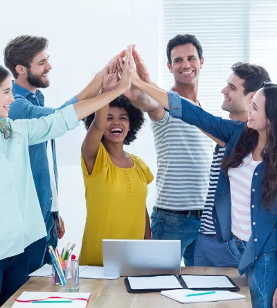 Diverse group of students celebrating teamwork with a high-five in a classroom setting.