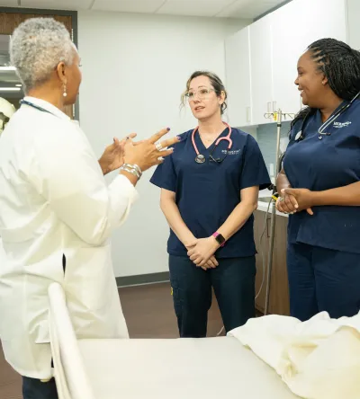 Herzing University nursing preceptor mentoring two nursing students during clinical training in a simulated healthcare setting