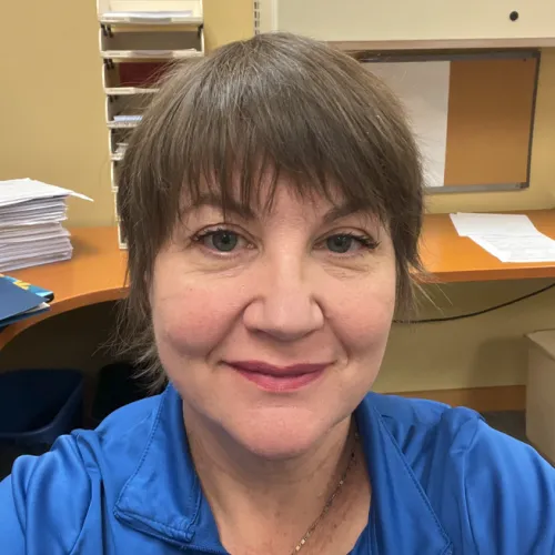 Woman in a blue shirt taking a selfie in an office 